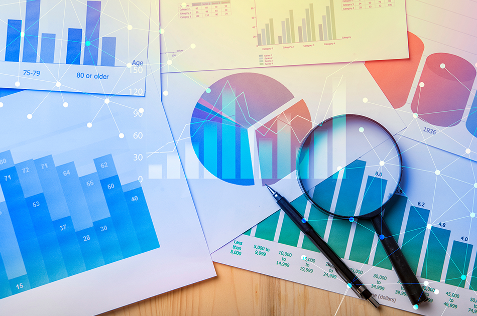 On a table, papers with colorful charts and graphs are scattered.